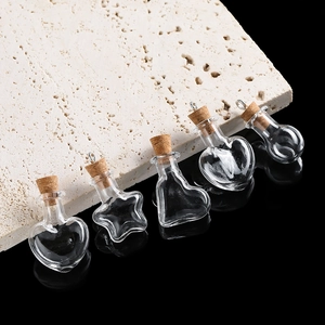 Close-up of five clear glass mini bottles in heart and star shapes with cork stoppers