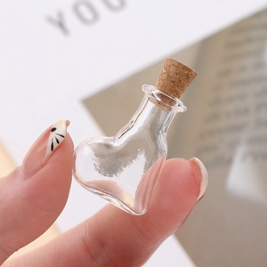 Macro shot of a mini heart-shaped clear glass bottle with a cork stopper held by hand