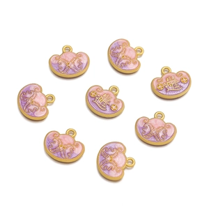 Macro detail of alloy cloud and ingot charms with pink enamel and gold-plated finish