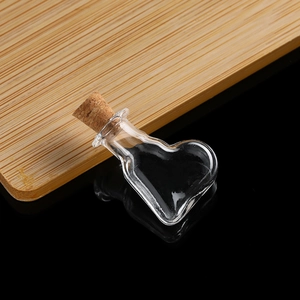 Close-up of heart-shaped mini glass bottle with cork stopper on a dark mirror surface