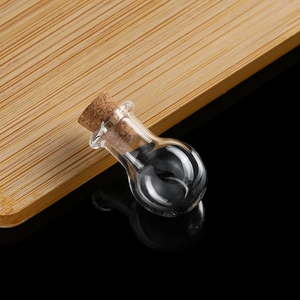 Detailed view of mini round glass wish bottle with natural cork stopper on wood surface