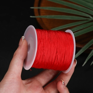 Close-up of bright red 0.4mm polyester cord on a white spool for DIY jewelry making