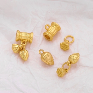 Matte gold lotus pod and root charms for DIY jewelry making on pink paper