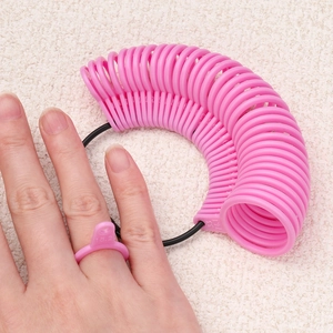 Pink ring sizer tool showing detailed scale markings on a finger for accurate sizing