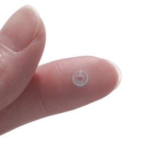 Macro shot of tiny 2x4mm transparent glass cat eye beads held on a fingertip for size