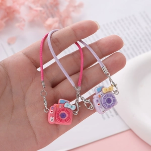Detail of pink and purple mini camera charms with cute resin bows and woven lanyards