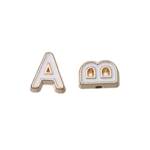 Macro detail of 10mm gold alloy alphabet beads A and B with white enamel oil drips