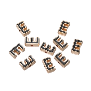 Macro shot of 10mm golden alloy letter E beads with black enamel for DIY jewelry