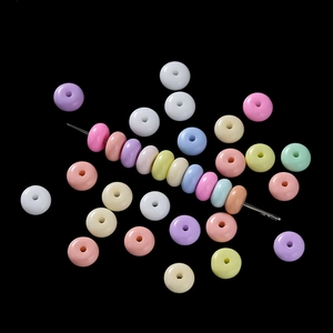 Détail macro de perles de verre pastel 3x6mm enfilées sur une aiguille argentée