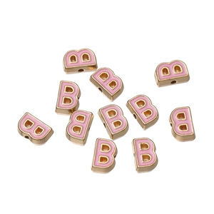 Close-up of pink enamel letter B bead with gold metal rim for DIY jewelry making