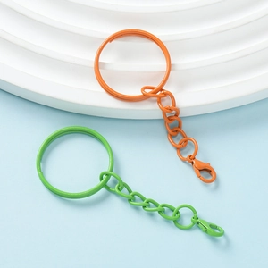 Close-up of orange and green painted metal keychains with lobster clasps and rings