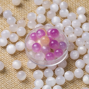 Detailed close-up of resin cat-eye beads in white and pink for DIY jewelry making
