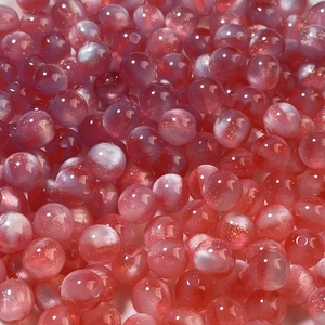 Macro detail of mermaid resin beads with pink purple gradient and shiny glitter sparkle