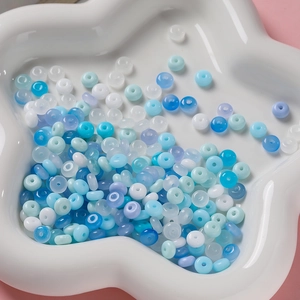 Gros plan de perles en verre bleues et blanches de 3x6mm dans un plateau en étoile