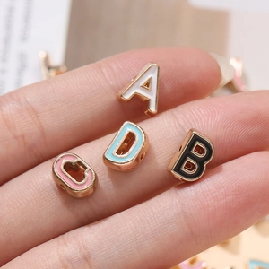 Macro detail of 10mm alloy alphabet beads with colorful drip oil for DIY jewelry