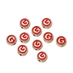 Detalle de cuentas redondas de esmalte rojo con inicial G dorada para joyas DIY