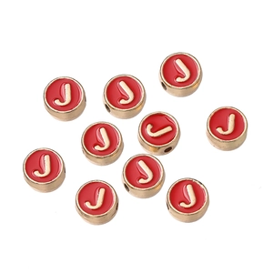 Detalle macro de cuentas de alfabeto en esmalte rojo con letra J dorada para joyas