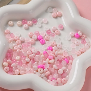 Détail macro de perles de verre 3x6mm roses et blanches dans un plat en céramique blanc