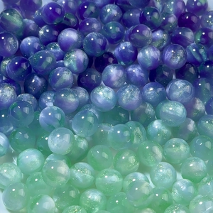 Macro shot of gradient mermaid resin beads with pearlescent shimmer for DIY jewelry making