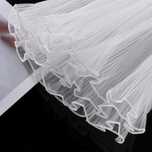Detail of white pleated tulle floral wrap with ruffled edges and wavy mesh texture