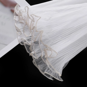 Detail of white pleated wave tulle with elegant gold embroidery edges for gift wrapping