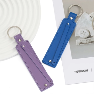 Détail de porte-clés en similicuir bleu et violet avec anneaux argentés sur plateau