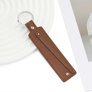 Gros plan sur un porte-clés en cuir PU marron avec anneau en métal et rivets