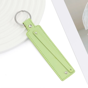 Détail d'un porte-clés en cuir PU vert clair avec coutures fines et anneau métallique