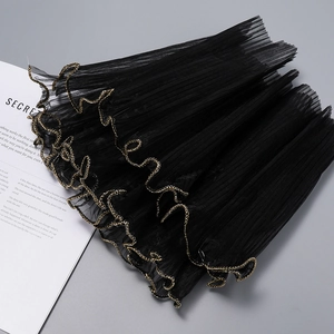 Macro detail of black pleated mesh fabric with gold wavy edge for floral gift wrapping