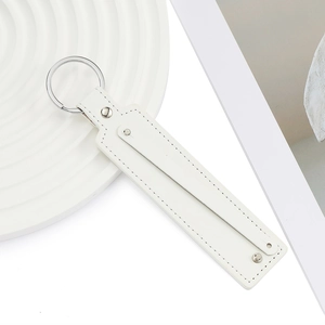 Gros plan d'un porte-clés en cuir PU blanc avec surpiqûres fines et anneau métallique