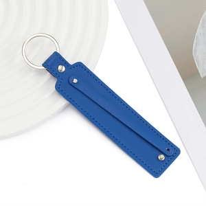 Détail du porte-clés en cuir PU bleu foncé avec rivets argentés sur plateau blanc