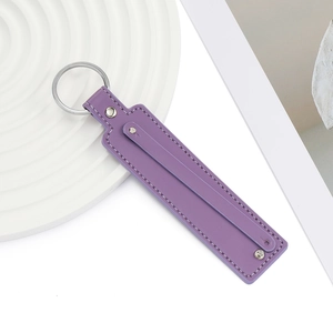 Détail d'un porte-clés en cuir PU violet foncé avec anneau argenté et coutures blanches