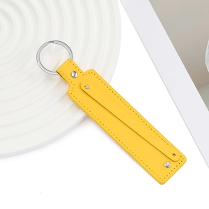 Gros plan d'un porte-clés en similicuir jaune vif avec anneau en métal et surpiqûres
