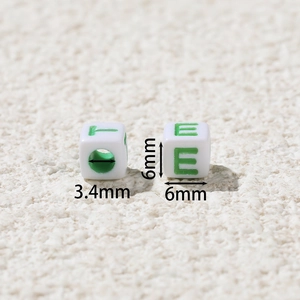 Macro detail of 6x6mm white acrylic cube beads with green letters and 3.4mm hole size
