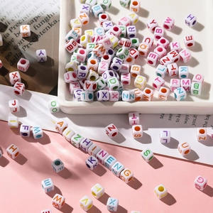 Macro shot of 6mm square acrylic letter beads on a pink background for DIY jewelry