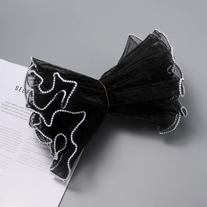 Detail of black wavy mesh cuffs with white pearl edges for elegant gift packaging