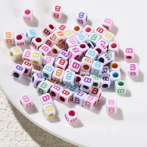 Close-up of 6x6mm white acrylic cube beads with colorful printed letter B for DIY jewelry