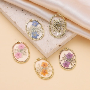 Macro view of five colorful dried flower resin pendants with gold scallop metal frames