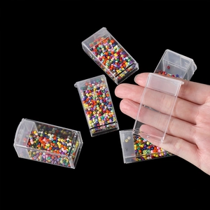 Detail of transparent plastic organizer box with flip lid showing colorful craft beads
