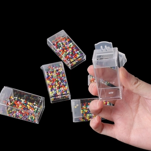 Detail of transparent plastic storage box with lid showing colorful seed beads inside