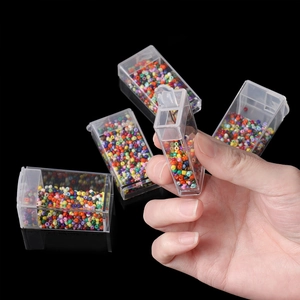 Macro detail of hand holding a clear plastic storage box filled with colorful DIY beads