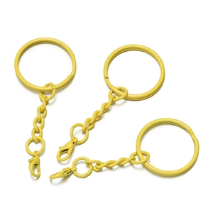 Drei gelb lackierte Metall-Schlüsselanhänger mit Karabiner und Gliederkette auf Weiß