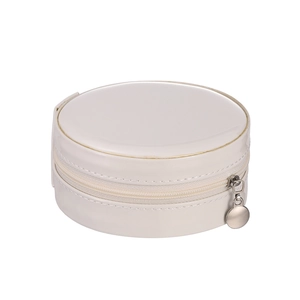 Close-up of a round jewelry box with beige patent leather and a silver zipper detail