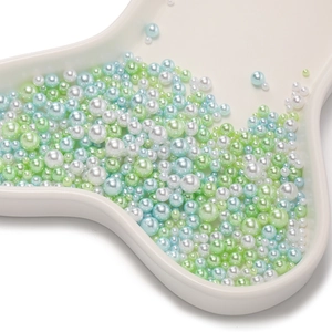 Close-up of mixed sizes Macaron ABS pearls in blue green and white on ceramic tray