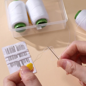 Close-up of using a yellow needle threader to pass white thread through a steel sewing needle