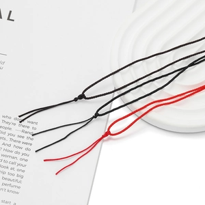 Détail de bracelets fins en corde tressée réglables en noir et rouge sur un plateau
