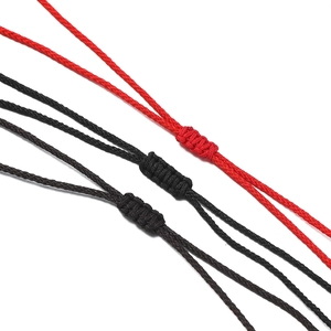 Détail macro de nœuds coulissants tissés à la main en rouge, noir et marron pour collier