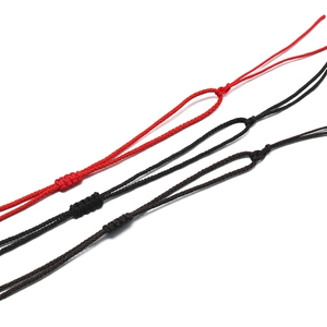 Détail de cordons de collier tressés réglables en rouge, noir et marron foncé