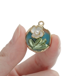 Detalle de un colgante de flor de esmalte azul con borde dorado y pétalos blancos