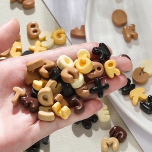 Close-up of resin alphabet beads for DIY crafts in earth tones held by a hand